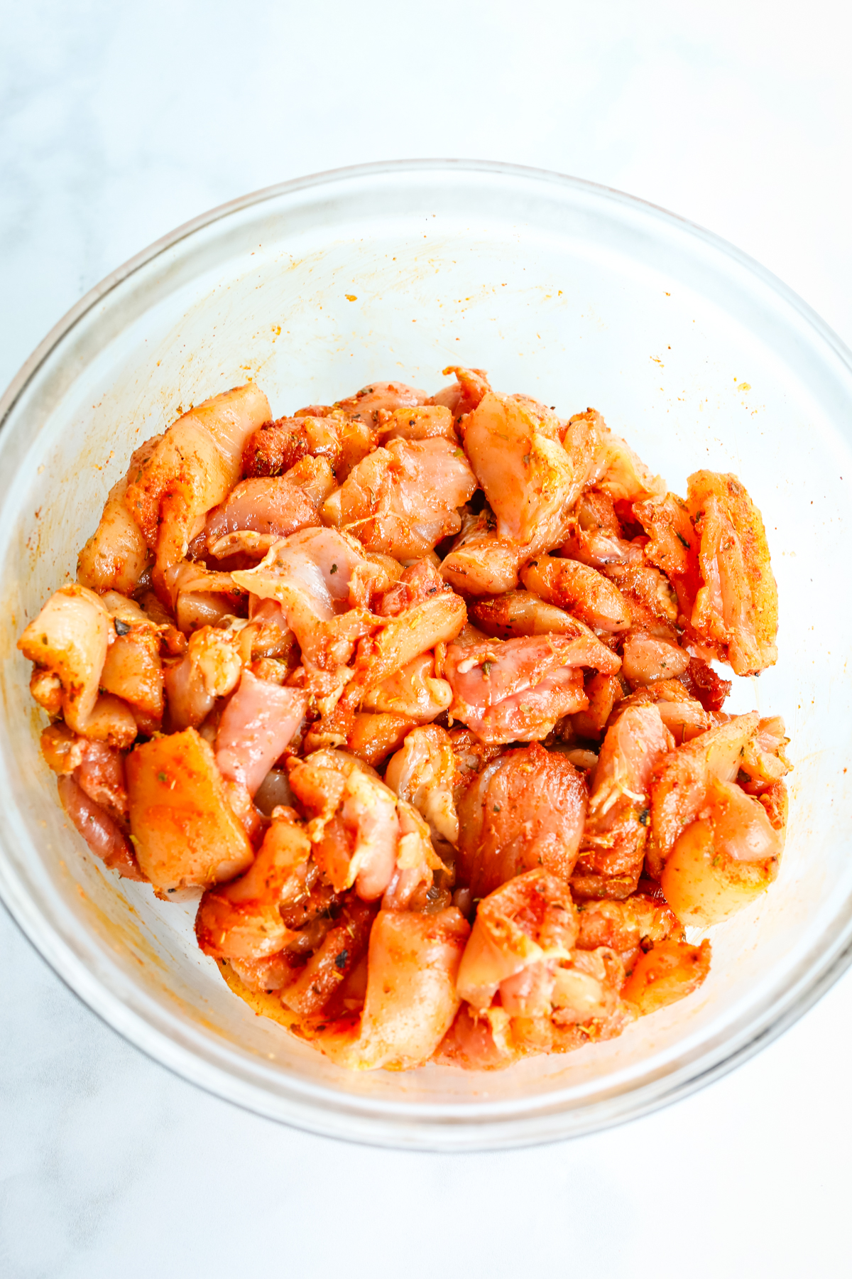raw chicken pieces in a bowl with seasoning