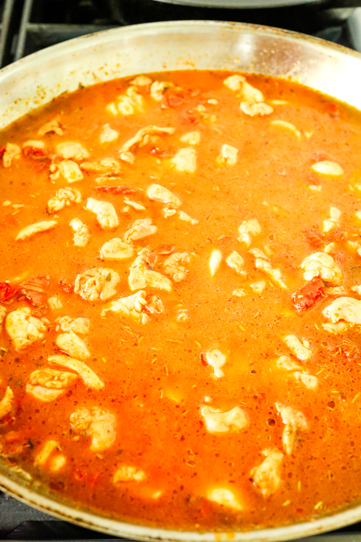 an orange liquid in a large pan with chicken