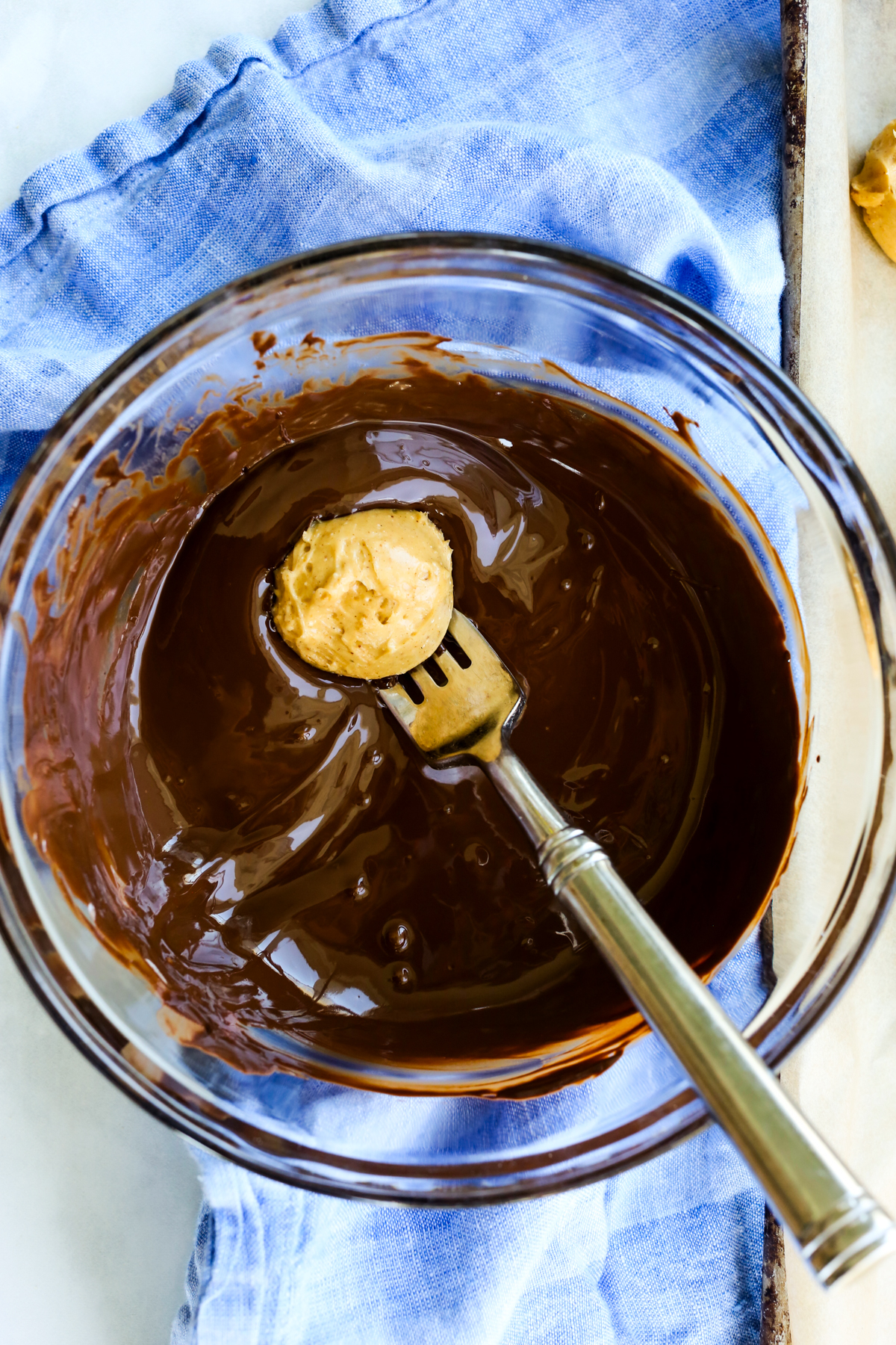 dipping a peanut butter ball into chocolate with a fork