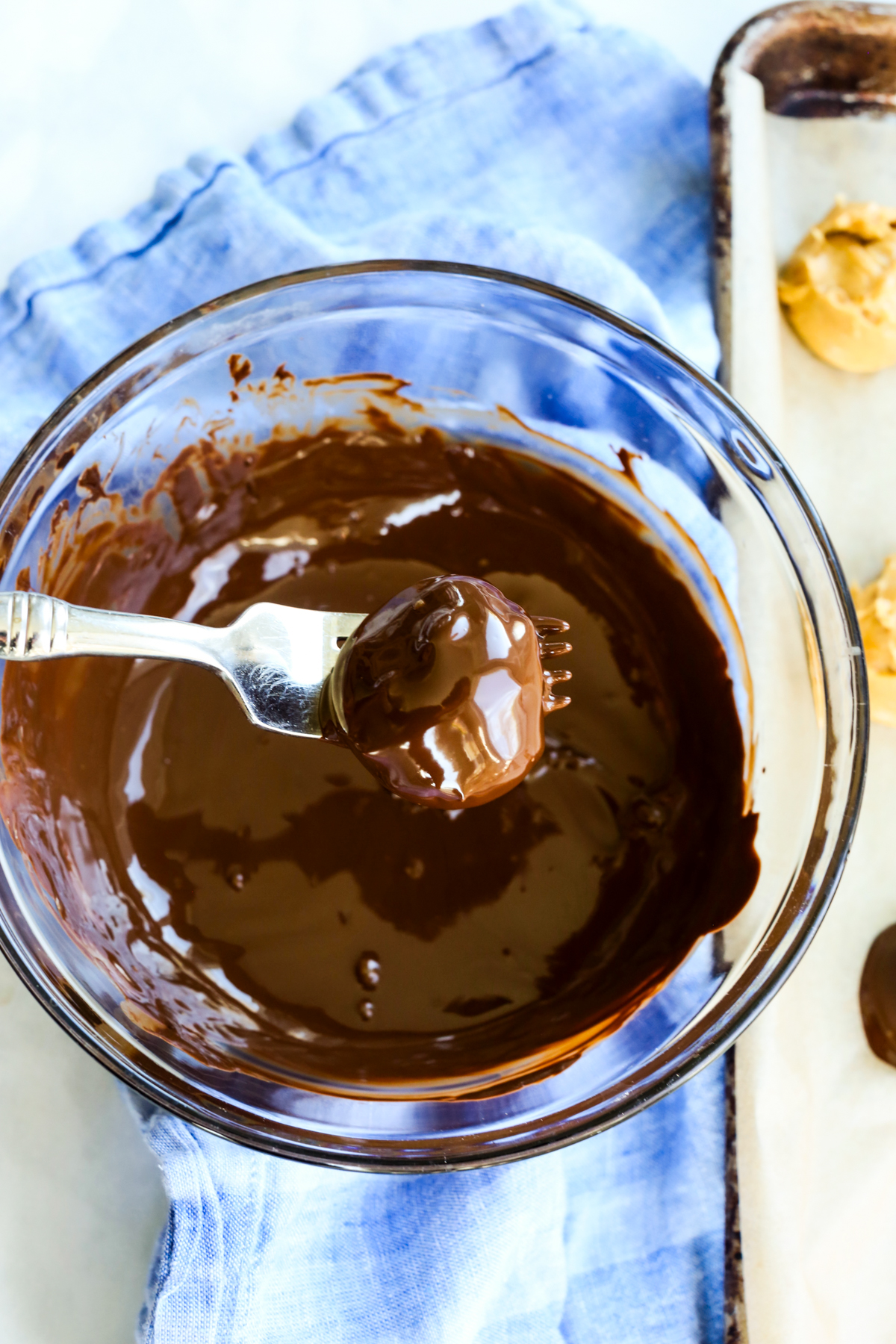a bowl of chocolate with a fork dipping a ball into the chocolate