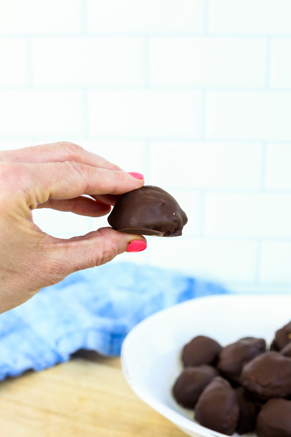 a hand holding a peanut butter protein ball covered in chocolate