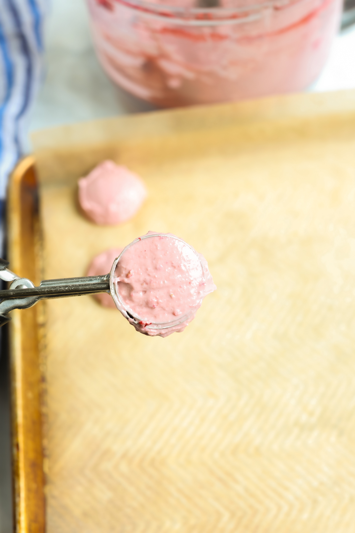 Scooping strawberry mixture onto a baking sheet lined with parchment paper
