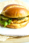 a hot honey chicken sandwich with lettuce and pickles on a plate