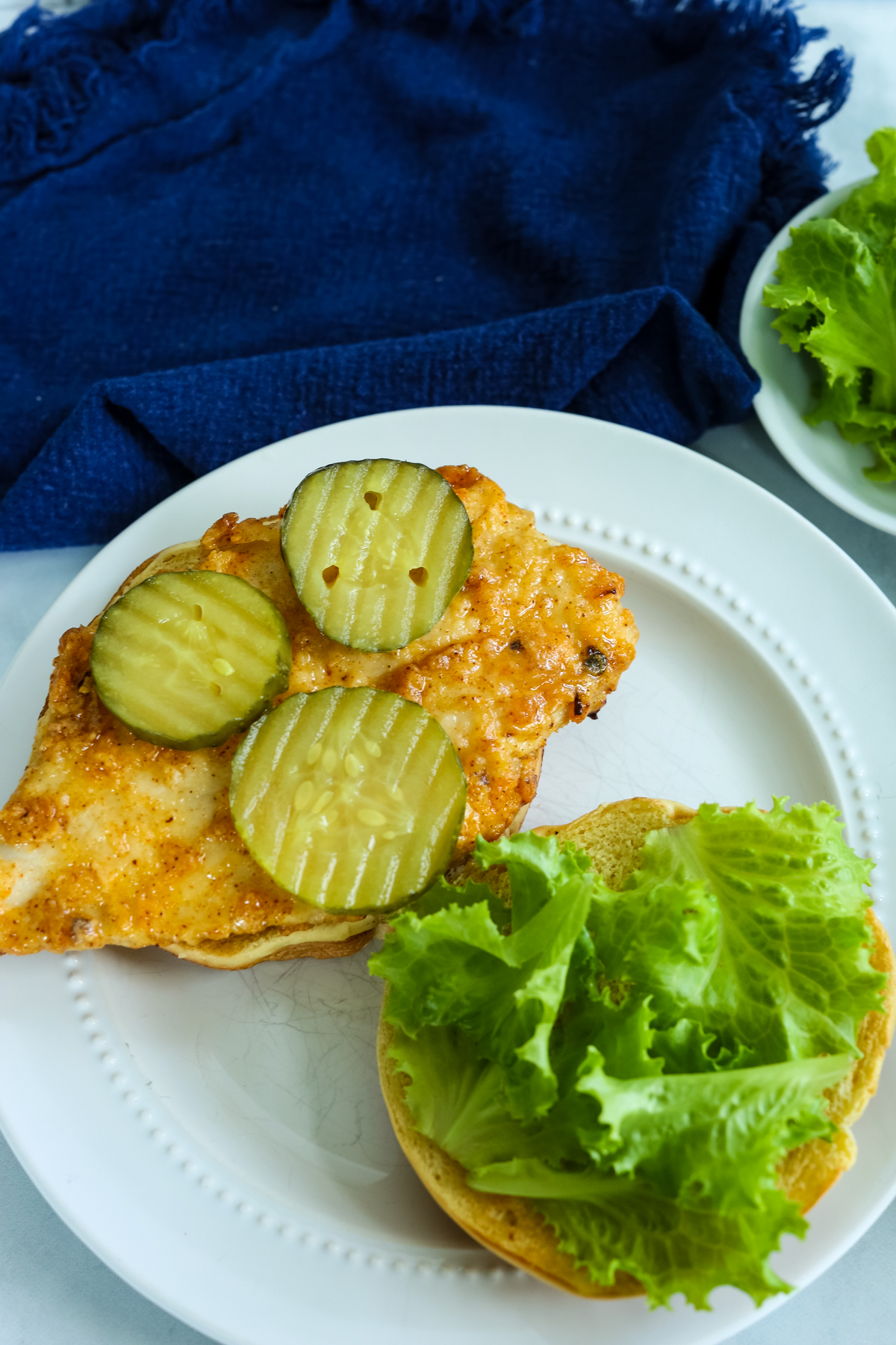 an open chicken sandwich with pickles on it 