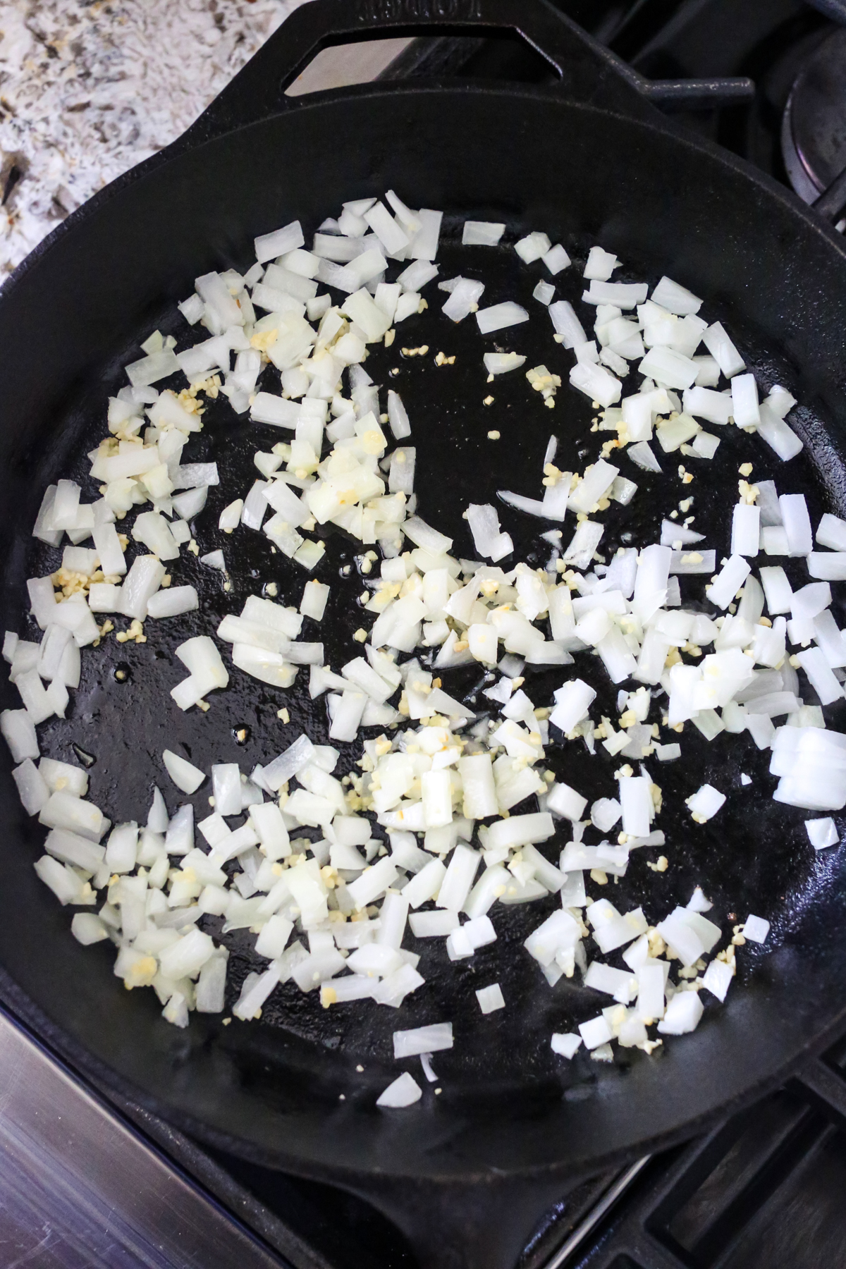 onions and garlic sautéing in a cast iron skillet 