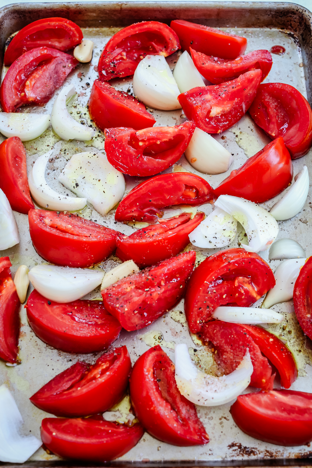 raw tomatoes, onions, and garlic a baking sheet
