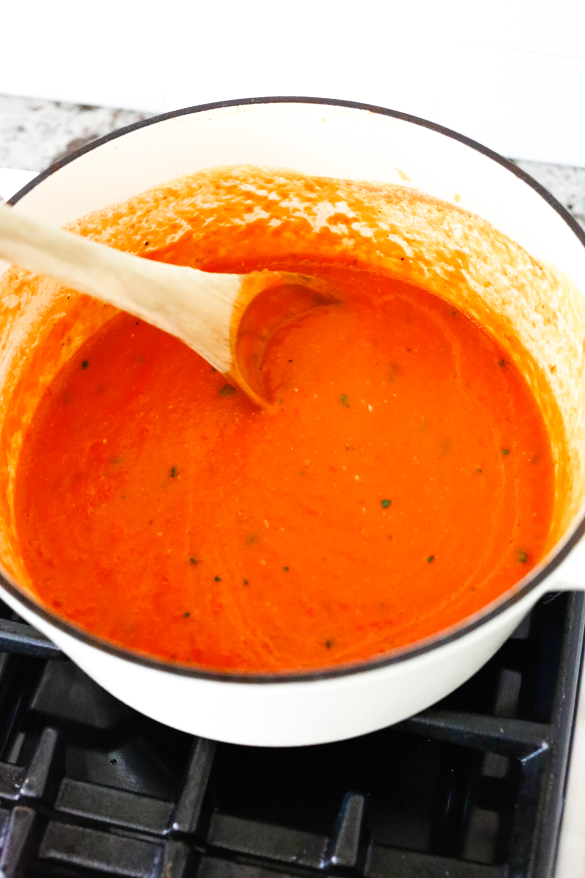 stirring roasted tomato soup in a pot