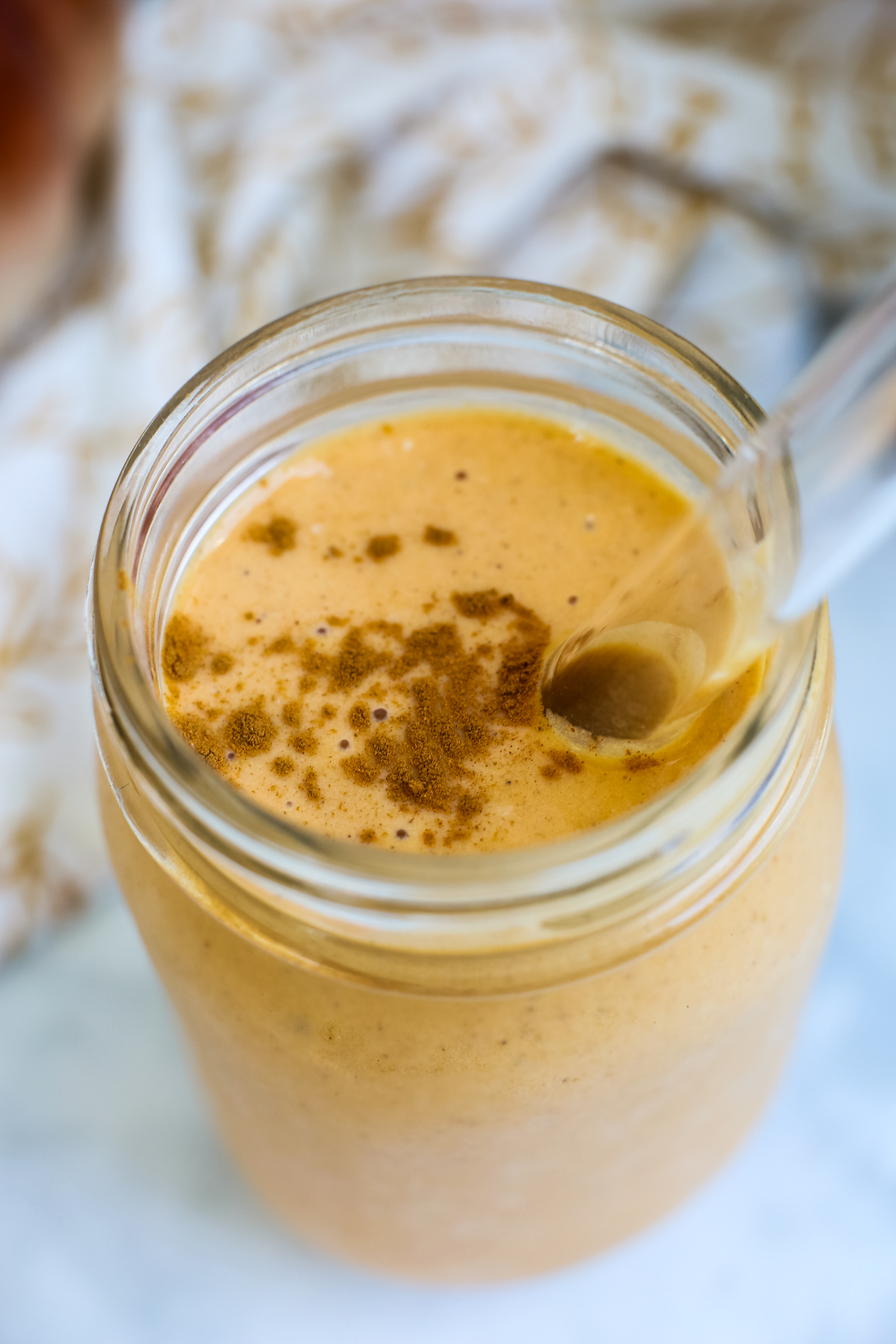 a close of photo of an orange hued smoothie with a dash of cinnamon on top