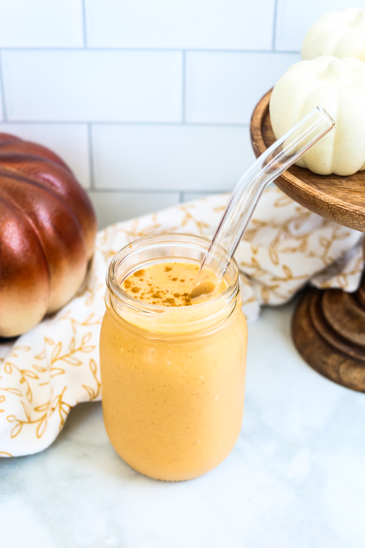 a pumpkin protein shake in a mason jar with a glass straw