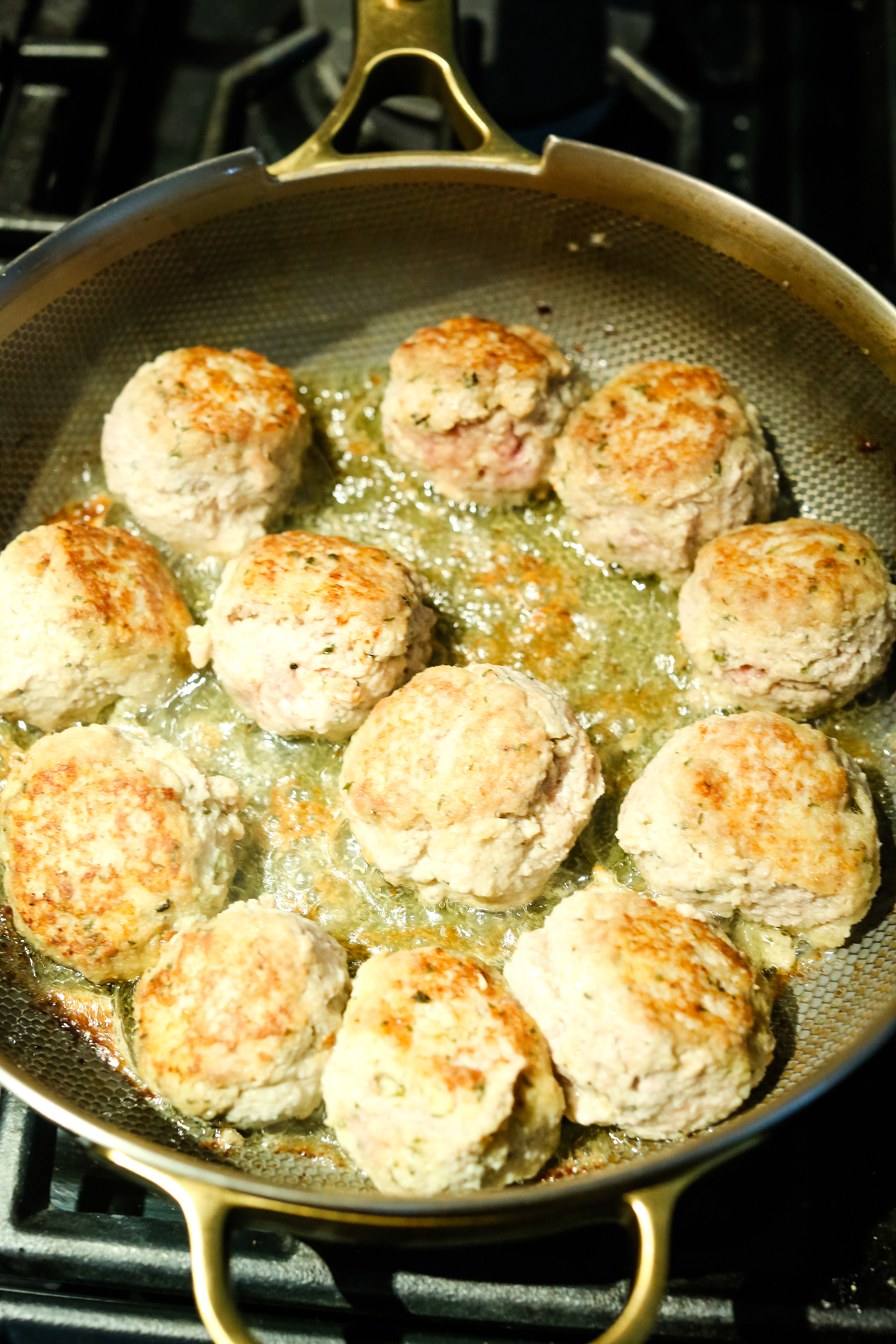 cooking meatballs in oil in a pan