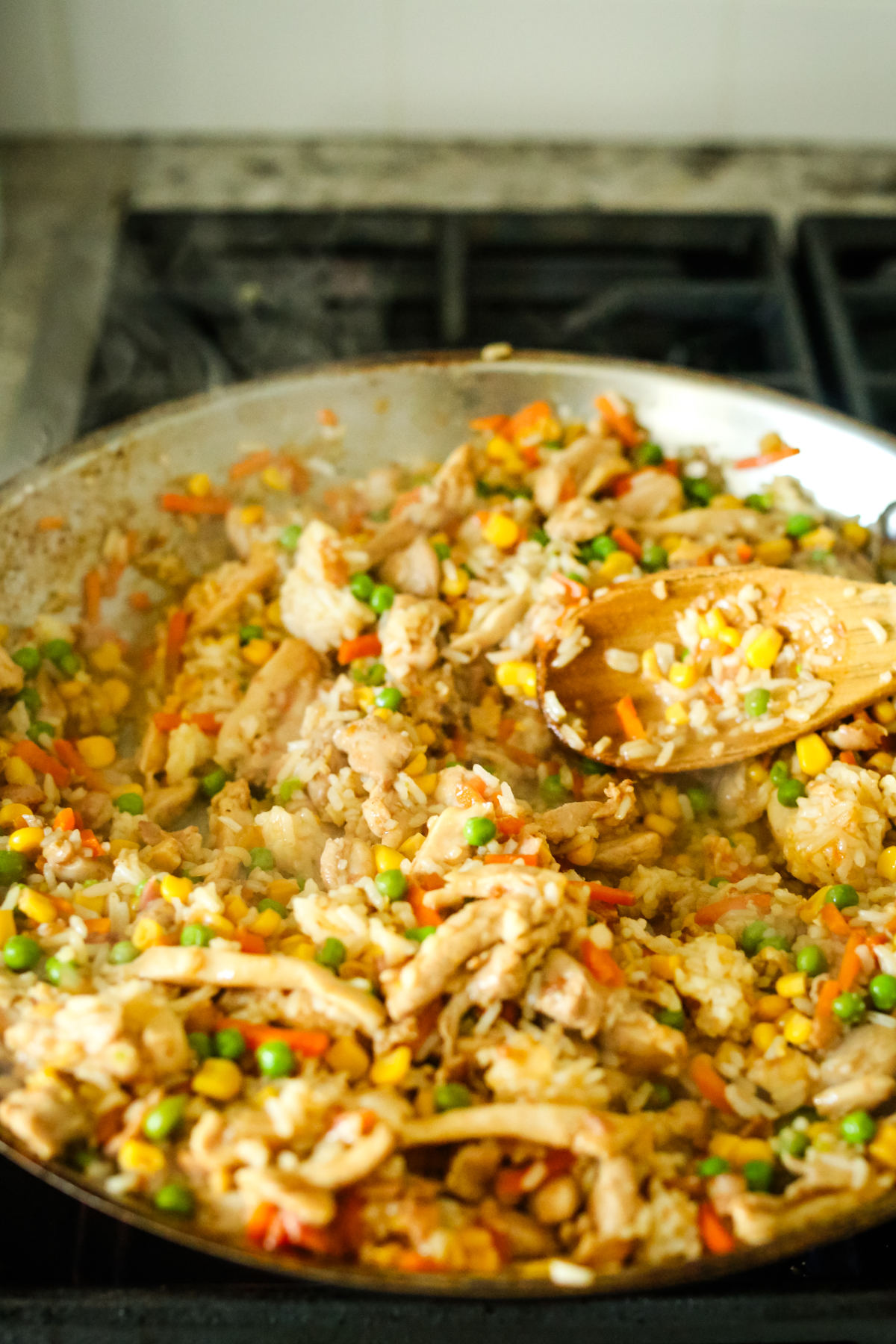 stirring chicken fried rice in a large skillet