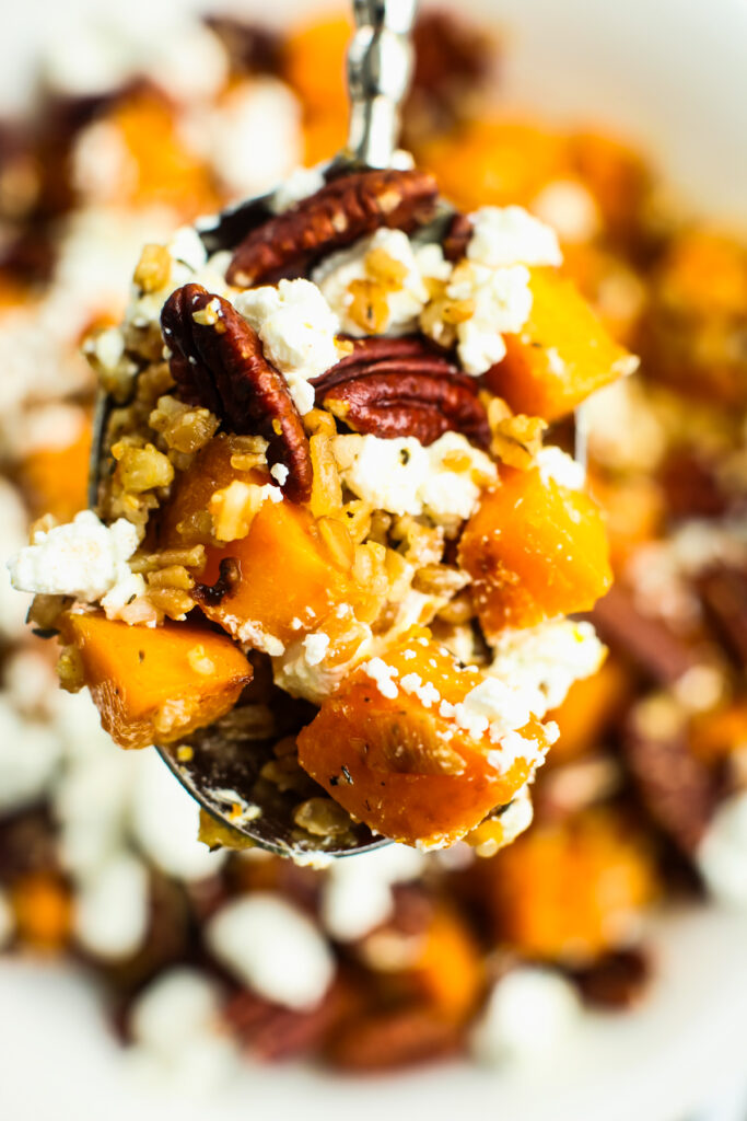 scooping a serving of Butternut squash with farro and goat cheese