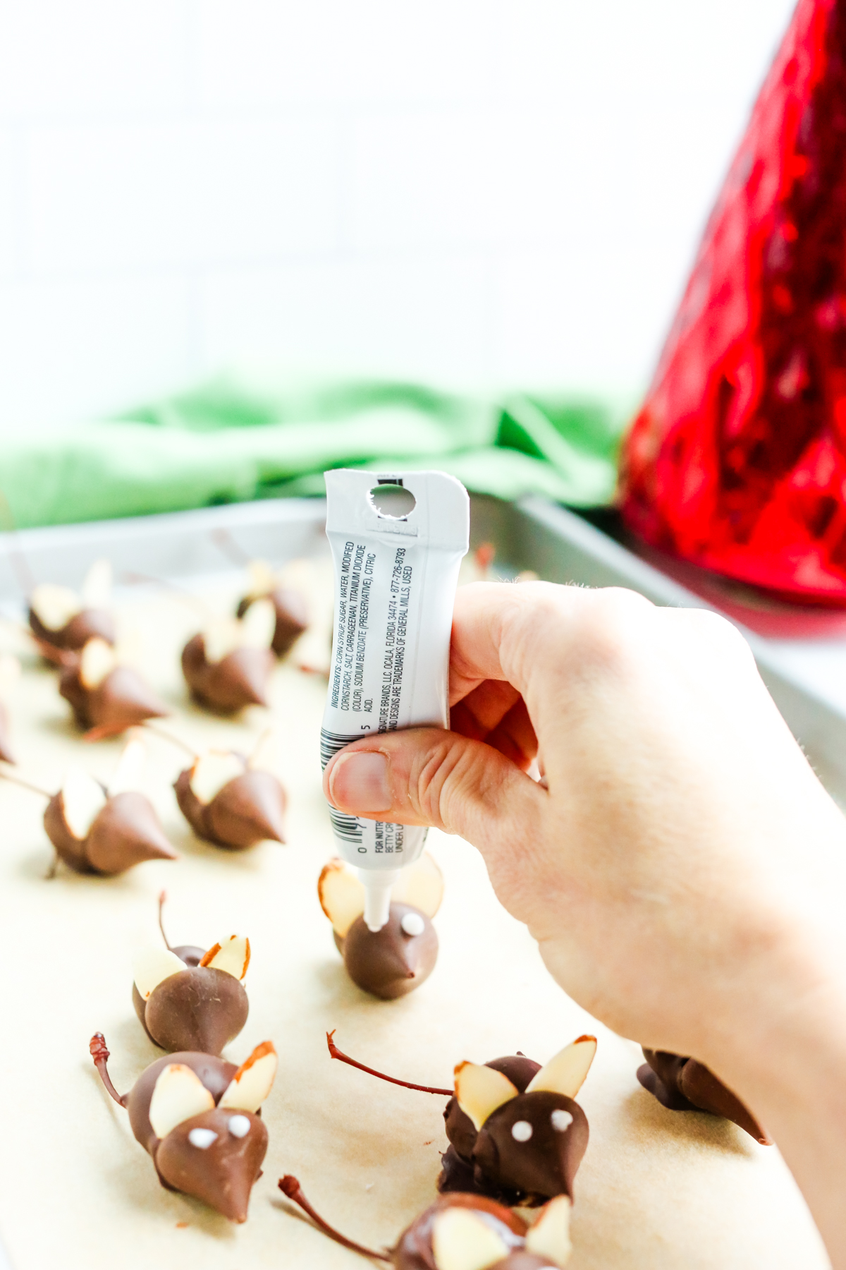 using white decorative icing to add eyes to the chocolate Christmas mice