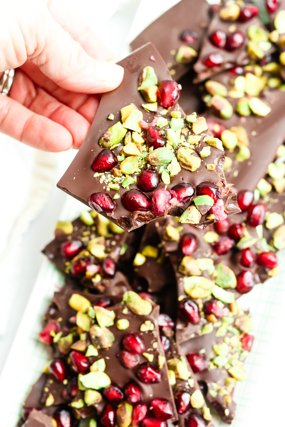 dark chocolate bark with pomegranate and pistachios in a. hand