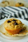 a close up shot of a muffin with chocolate chips with the paper wrapper partially removed
