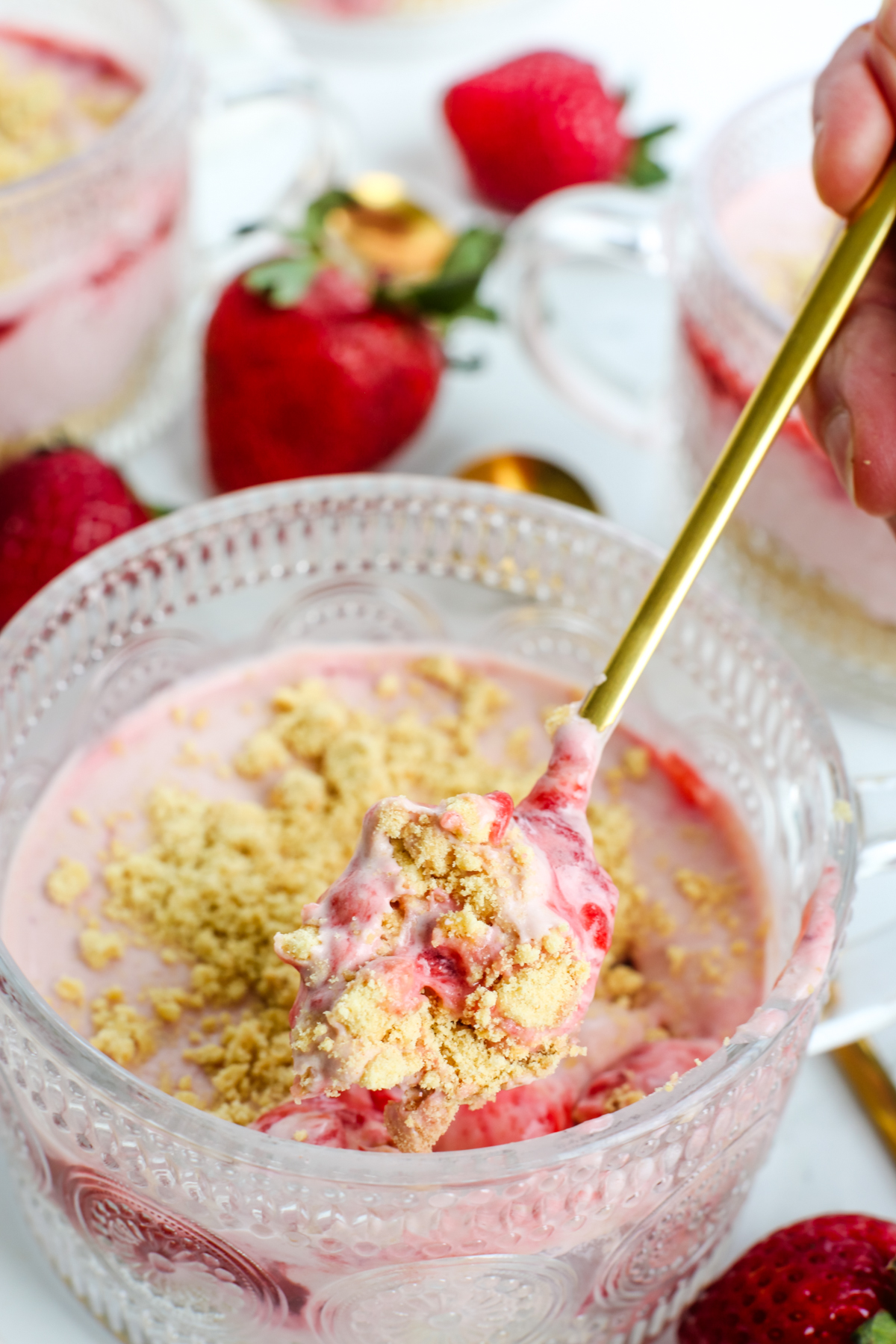 a dessert in a glass cup with a gold spoon taking a scoop out 