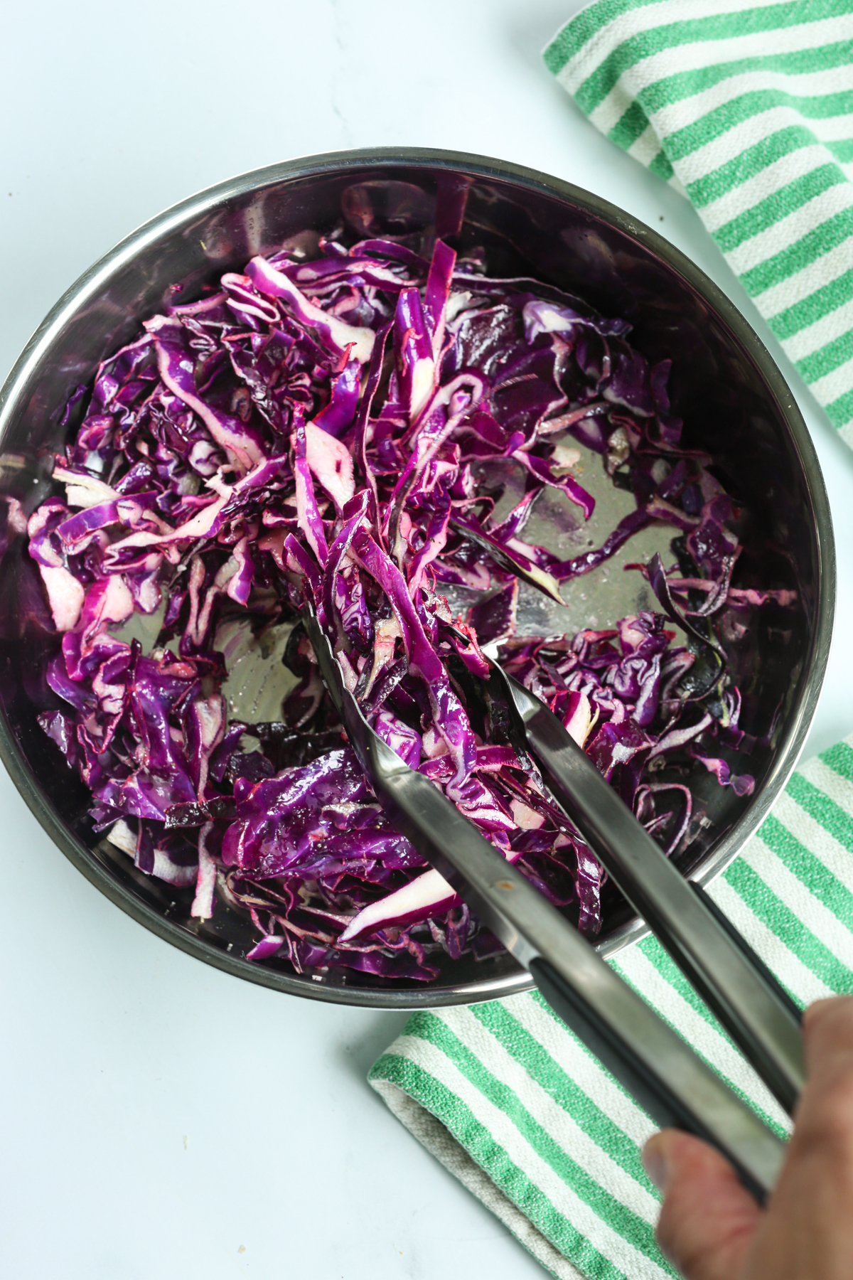 shredded red cabbage in a bowl with tongs
