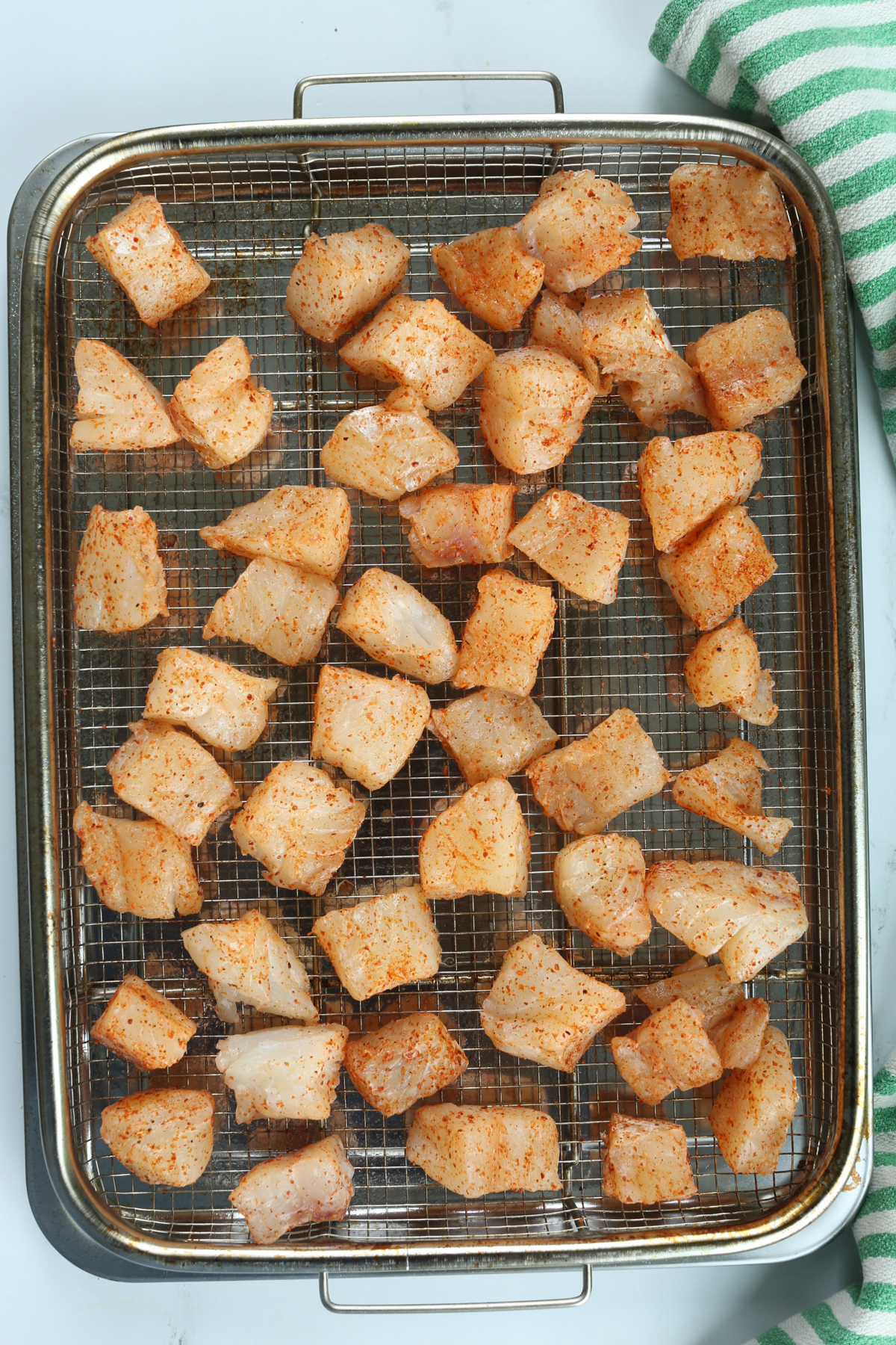 seasoned fish pieces on an air fryer tray