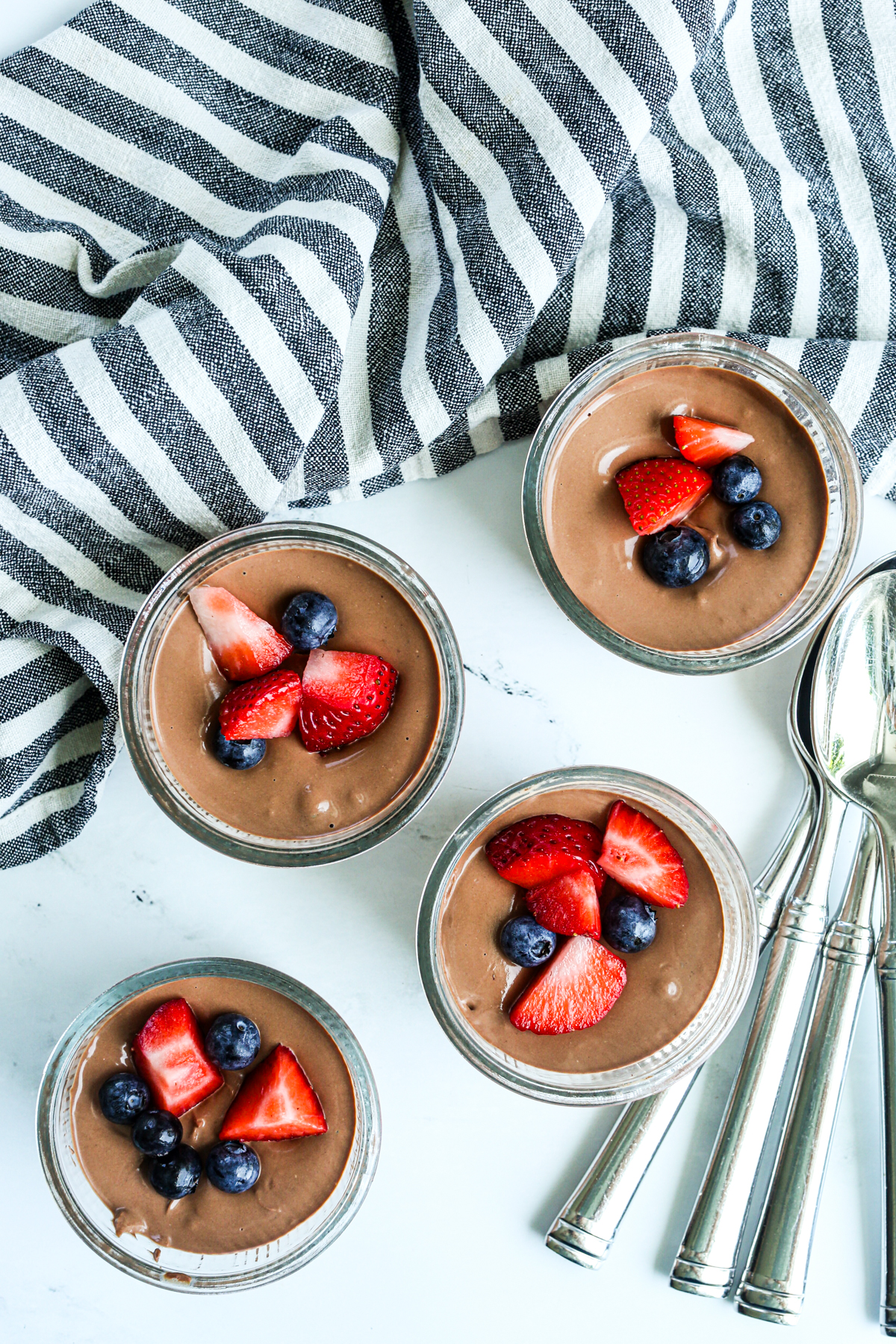 4 dessert cups with chocolate mousse topped with berries