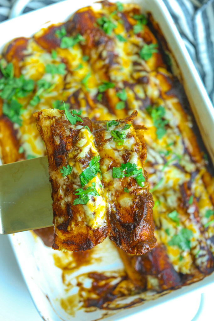 a pan of chicken enchiladas with two on a spatula